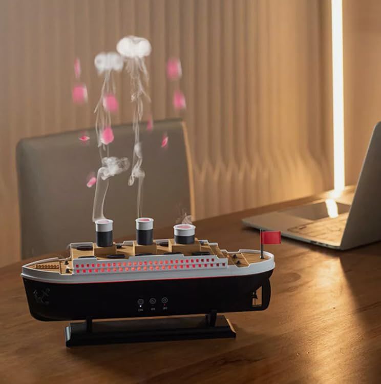Titanic ship humidifier diffuser releasing mist on wooden desk next to laptop in warm light